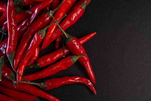 istock Fresh red chili peppers on dark background 2246223765