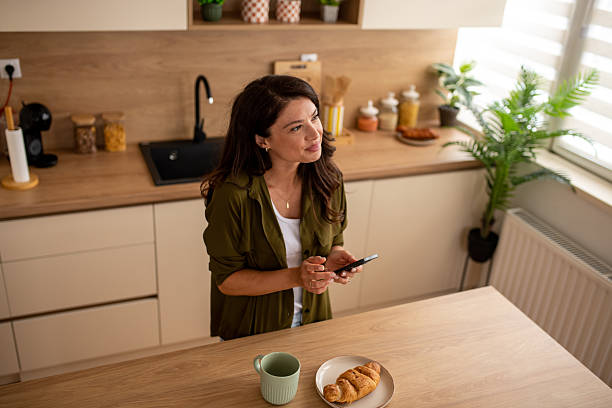 istock Woman smiling at phone while eating breakfast 2246225210