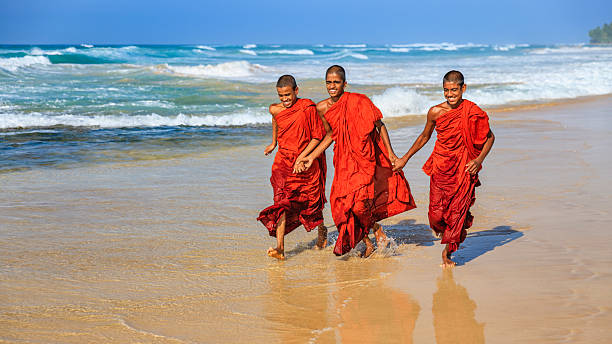 Three Sri Lankan young buddhist monks walking on the beach near Galle, Sri Lanka