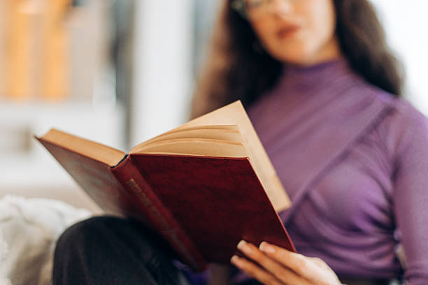 istock Beautiful woman reading interesting book at home, selective focus in hands 2246225349