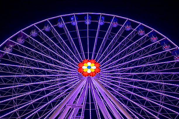 istock Illuminated Ferris Wheel Glowing With Purple Lights Against Night Sky 2246226519