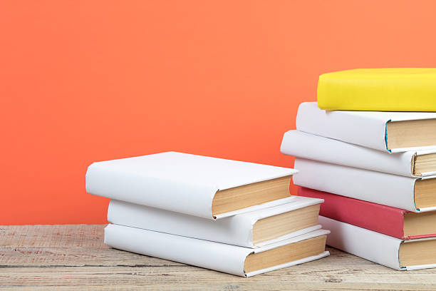 istock Books stacking. Books on wooden table and orange background. Back to school. Copy space for ad text. 2246226565