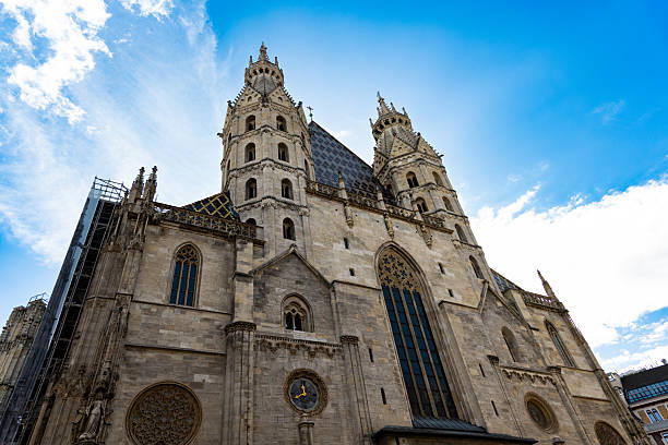 This magnificent Gothic cathedral in Vienna features intricate twin towers, ornate architecture, and a vibrant blue sky backdrop. A historic landmark in Austria's capital city, its stunning design highlights centuries-old craftsmanship and cultural heritage.