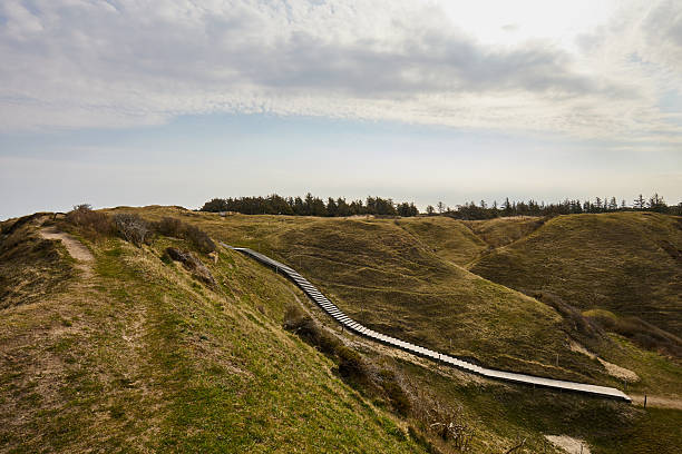 A boardwalk passing through hilly landscape against sky on a sunny day