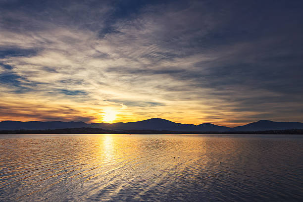 istock Vibrant Sunset Over Calm Lake with Mountain Silhouette 2246228057