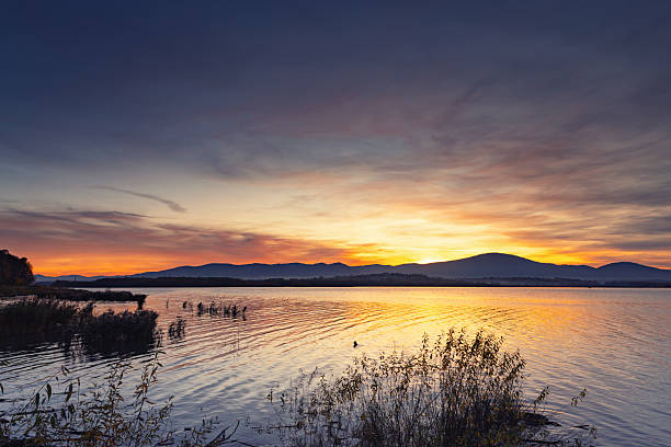 istock Vibrant Sunset Over Calm Lake with Mountain Silhouette 2246228071