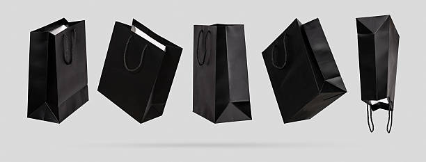 istock Black paper shopping bags flying from different sides, light gray background. Creative concept shopping discounts, sale purchase in store. Cut out template objects for commerce design. Mock up. Banner 2246229351