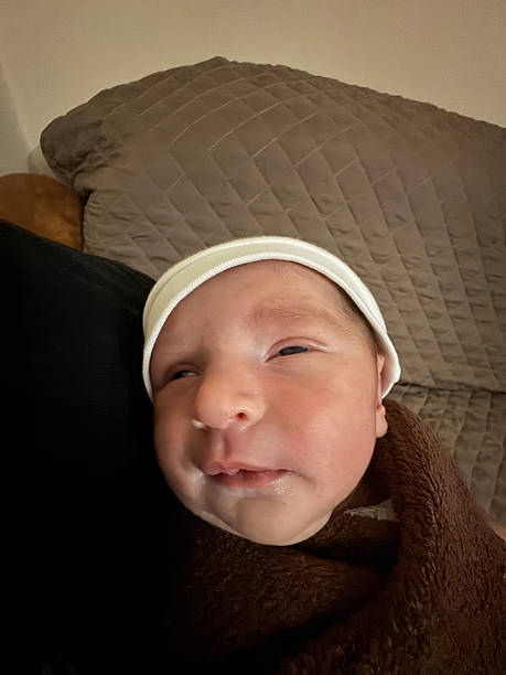 Newborn wrapped in brown blanket looking up