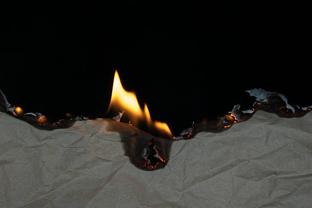 istock burning paper, glowing edge of paper on a black background 2246231052