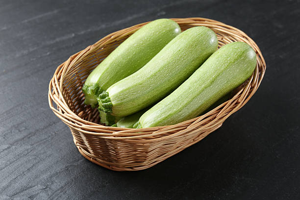 istock Fresh ripe zucchinis in wicker basket on black textured table 2246231895