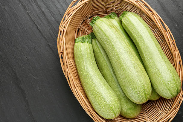istock Fresh ripe zucchinis in wicker basket on black textured table, top view. Space for text 2246231969