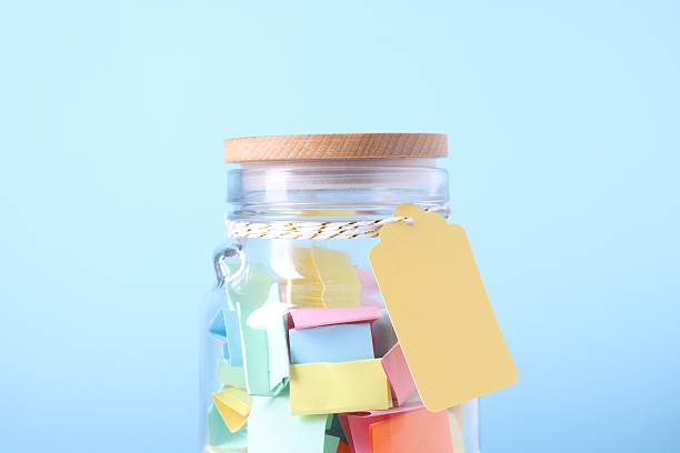 istock Colorful paper pieces in glass jar on light blue background, closeup. Message notes 2246233341