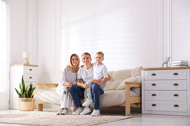 istock Woman with air conditioner remote control, her husband and son on sofa at home 2246234496