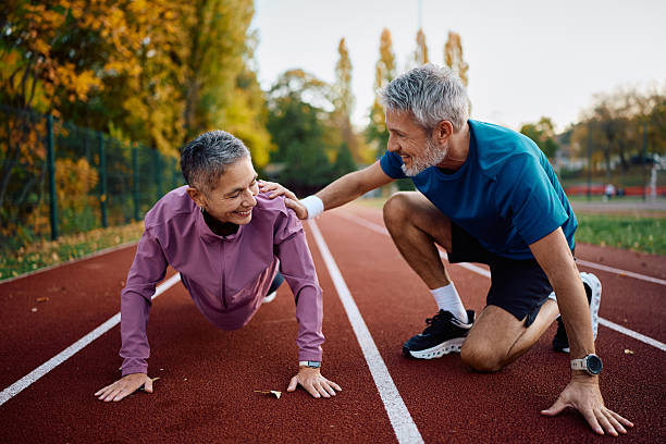 istock Happy mature woman doing push-ups while exercising with her husband in autumn park. 2246236344