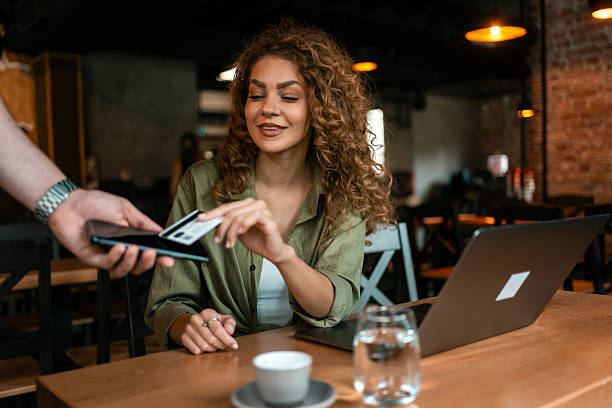 istock Young woman using smartphone at cafe during afternoon meeting with laptop on table 2246237180