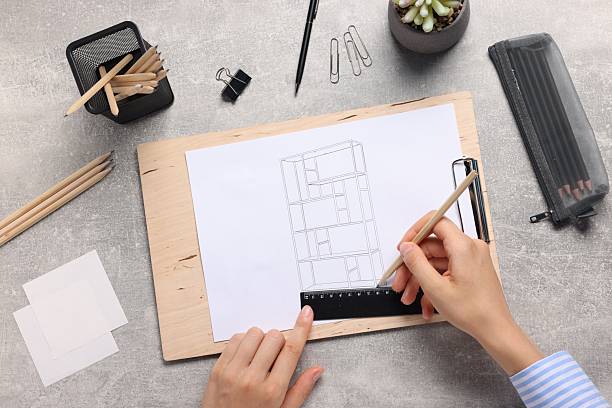 istock Woman drawing sketch of shelving unit at grey table, top view 2246237241