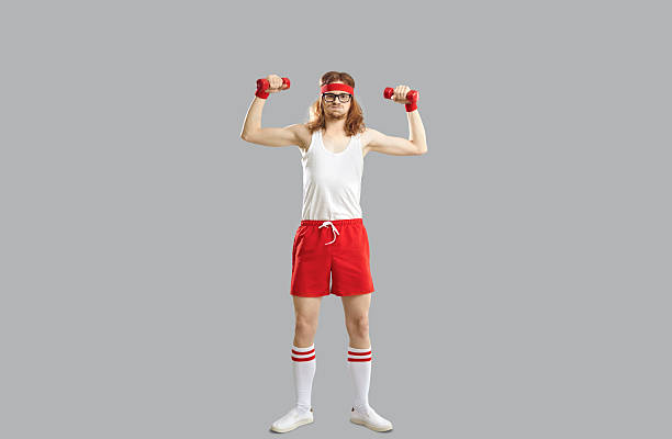 istock Funny smiling hipster skinny young guy doing workout with dumbbels 2246239102