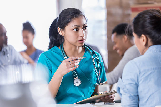 istock Young Hispanic nurse attentively listens while holding a thermometer and clipboard. 2246239516