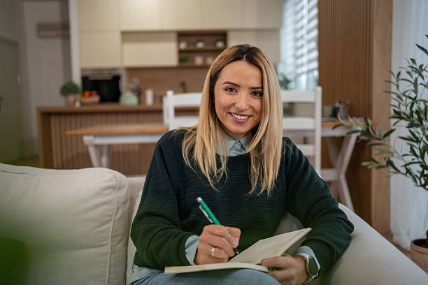 istock Young adult woman writing in notebook at home 2246242549