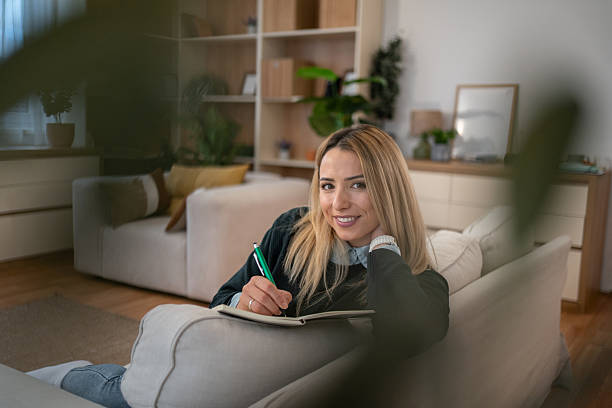 istock Woman writing journal on couch in living room 2246242567
