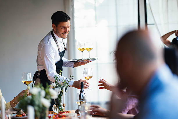 kellner serviert freunden wein während einer eleganten mittagsfeier - gastronomiebetrieb stock-fotos und bilder