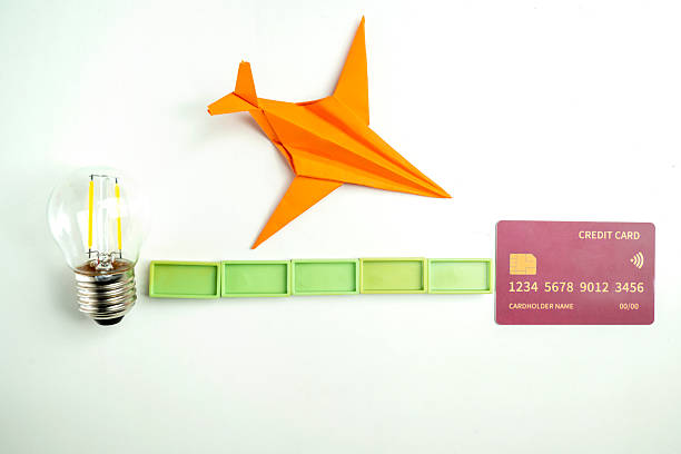 Top view of a lightbulb with rectangular blocks and a credit card with a paper airplane on a white background. Concept of finance and travel
