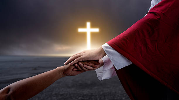 istock Jesus Christ hand offering a helping hand with a Christian cross on dark dramatic sky background. Concept of Christianity, religious, faith, Jesus, or belief 2246247247