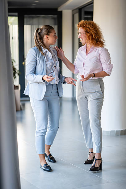 istock Two businesswomen having conversation in modern office hallway 2246248973