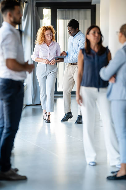 istock Business professionals networking and discussing ideas in modern office hallway 2246249199