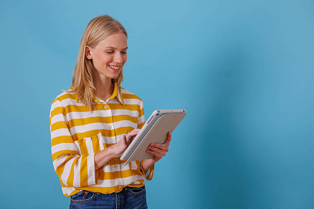 istock Woman smiling while using a digital tablet for online shopping and social media on blue background 2246251055