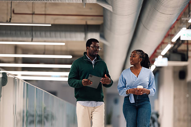 istock Business colleagues walking and discussing in modern office lobby 2246253299