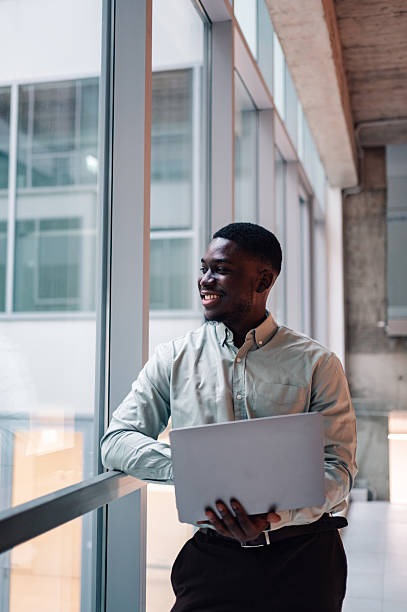 istock Young black man smiling holding laptop in modern office 2246253630