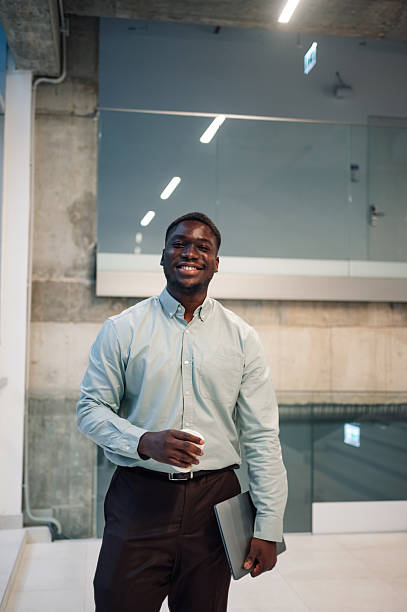 istock Young black businessman smiling while holding laptop and coffee 2246253654