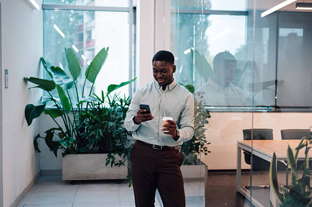 istock Black businessman using smartphone having coffee break in modern office 2246253694