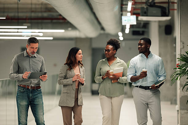 istock Diverse business professionals walking in office hallway talking 2246254274