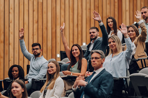 istock People raising hands asking questions at conference 2246260395