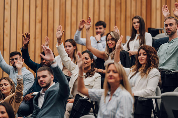 istock Business people raising hands asking questions at conference 2246260414
