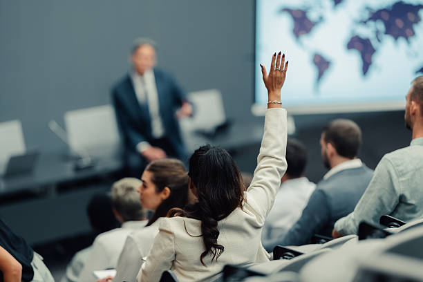 istock Woman raising hand asking question at business conference 2246260513