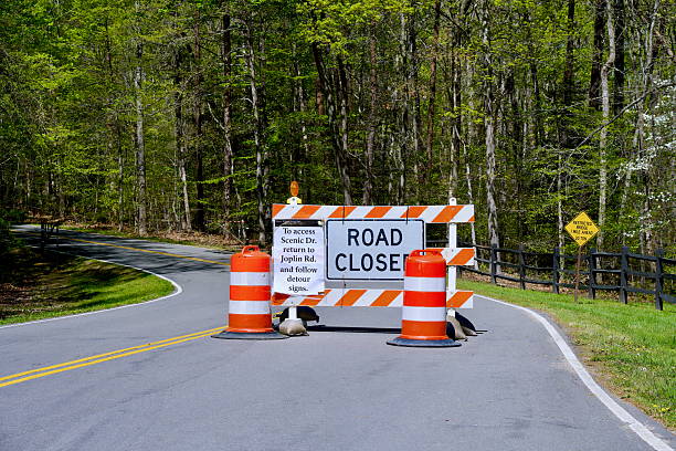 Triangle, Virginia, USA - April 16, 2025: Construction cones and a barrier with a “Road Closed” sign blocks visitors from using the main road through Prince William Forest Park on a Spring day.
