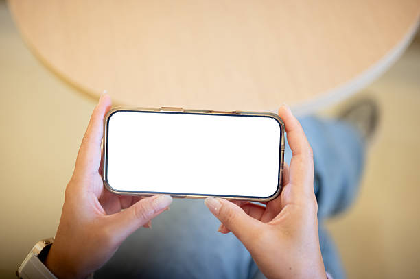 istock Woman hands holding white screen smartphone horizontally watching playing game sitting at cafe table 2246274905