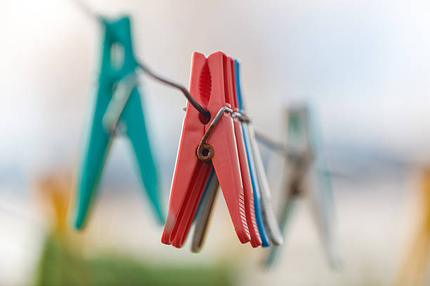 A row of clothespins hanging on a clothesline. The clothespins are red, blue, and green