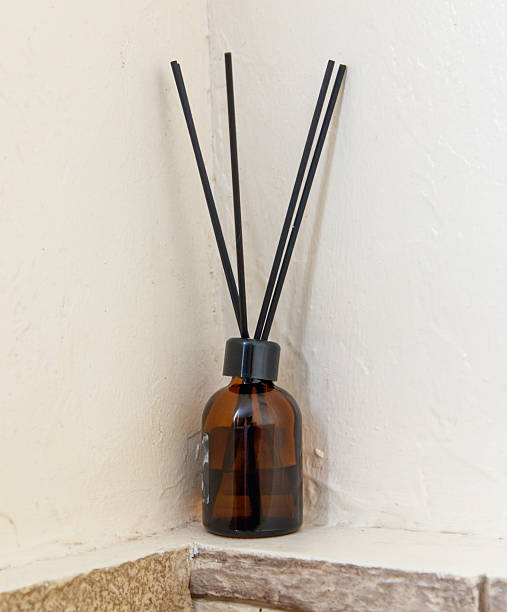istock A brown bottle with a black cap and four black sticks inside. The bottle is hanging on the wall 2246287680