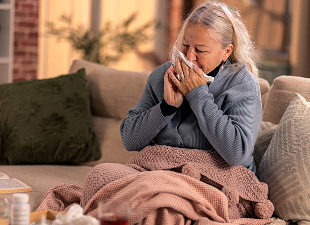 istock Elderly woman with flu symptomes sitting on sofa at home 2246287856