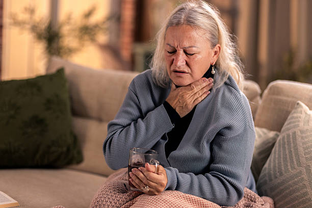 istock Elderly woman with flu symptomes sitting on sofa at home 2246287871