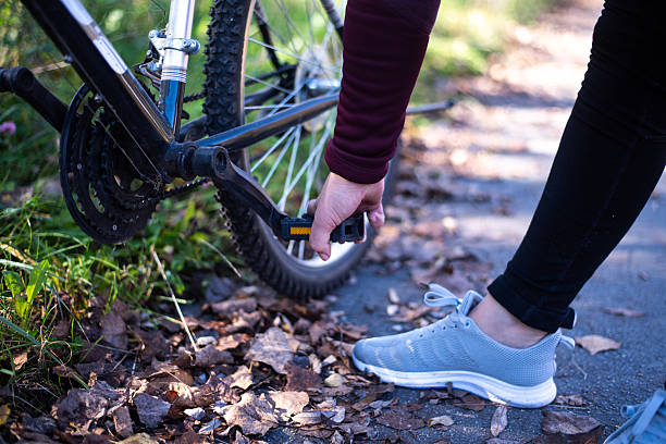 Close up photo a mature  woman adjusts a bicycle pedal.
