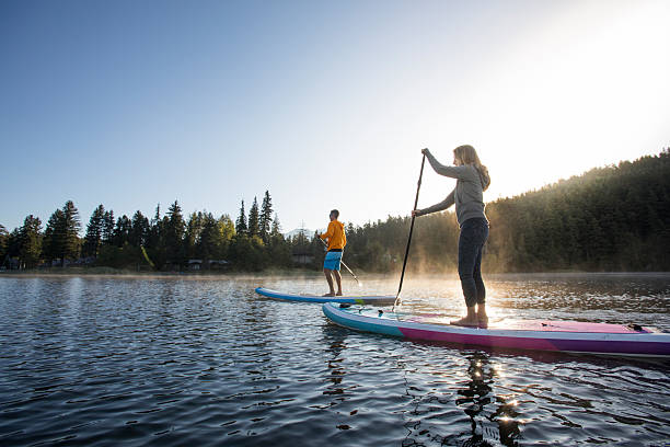 istock Couple paddle stand up paddleboards on tranquil mountain lake 2246291054