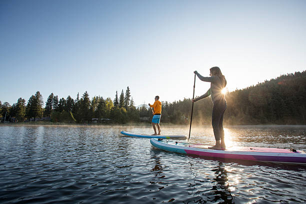 istock Couple paddle stand up paddleboards on tranquil mountain lake 2246291057