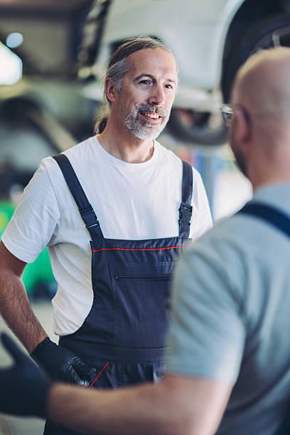 istock Two auto mechanics talking in the garage 2246291526