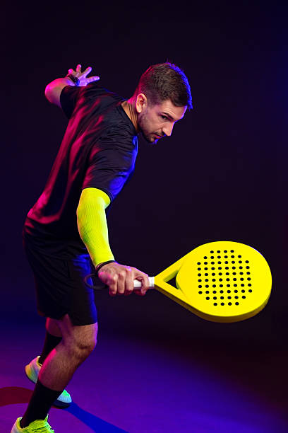 istock Player practicing with a yellow paddle in a colorful sports studio at night 2246296242