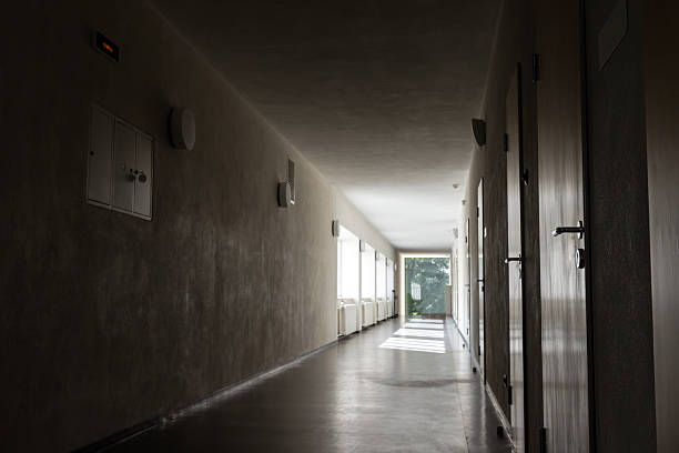 istock A quiet, dim corridor with closed doors on the right and natural light at the far end 2246297612